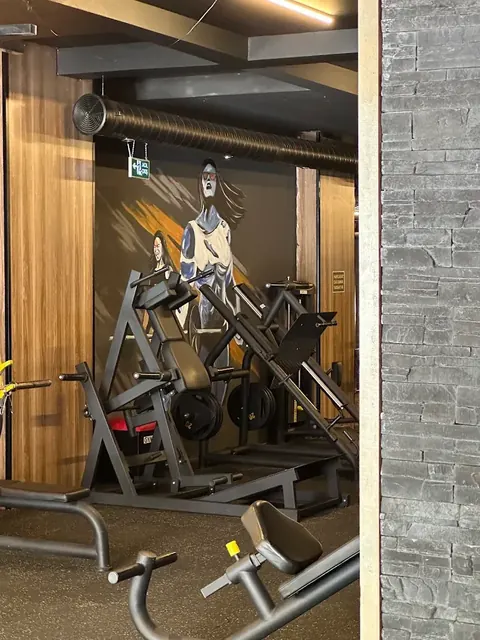 Boyalı duvar resmi önünde hack squat ve bacak makineleri
