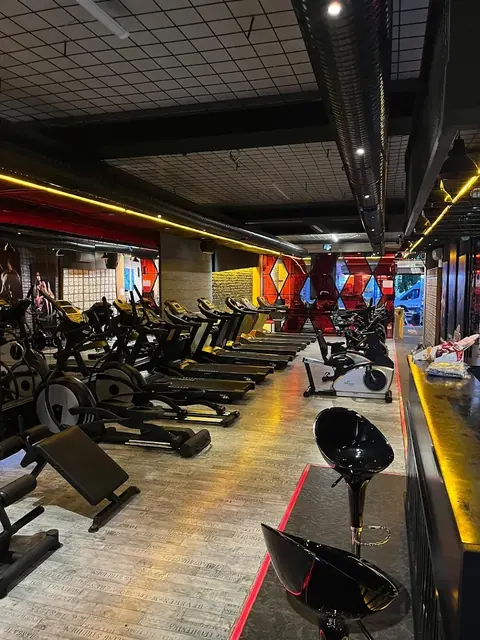 Sıcak ışıklar altında uzun koşu bandı sırası ve bar tabureleri